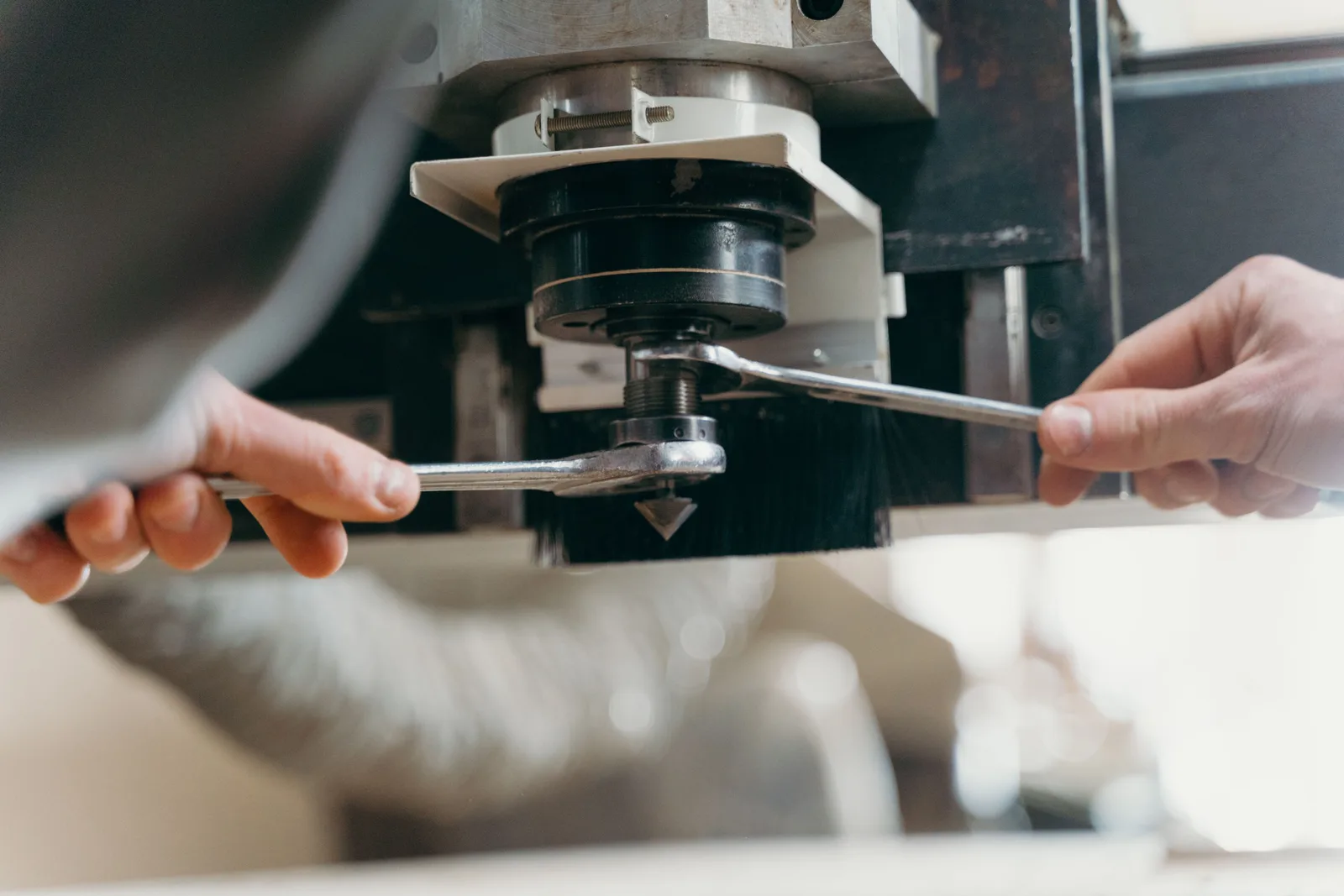 Close-up of hands adjusting a CNC machine using wrenches in an industrial setting. Brands that matter in car wash equipment