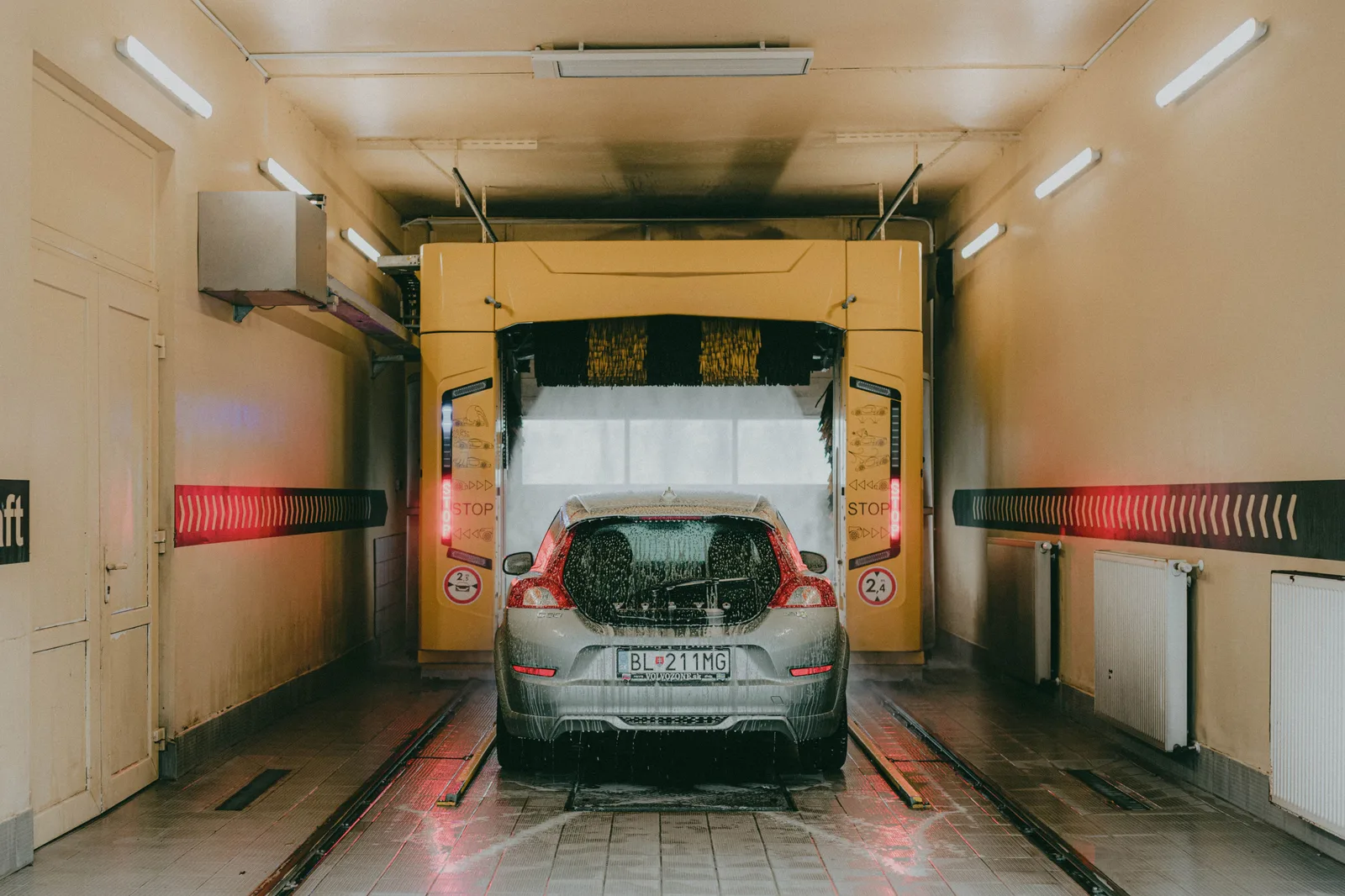 A modern car undergoing an automated interior car wash with bright lights and soapy water. Car wash water discharge rules: EPA and state permits, drainage and bay throughput