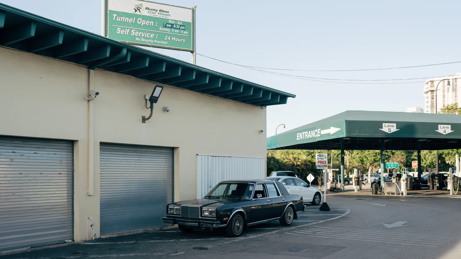 Vintage car parked at urban car wash with retro signage under clear sky. What Is a Good Cars-Per-Hour Rate for a Car Wash in 2027?