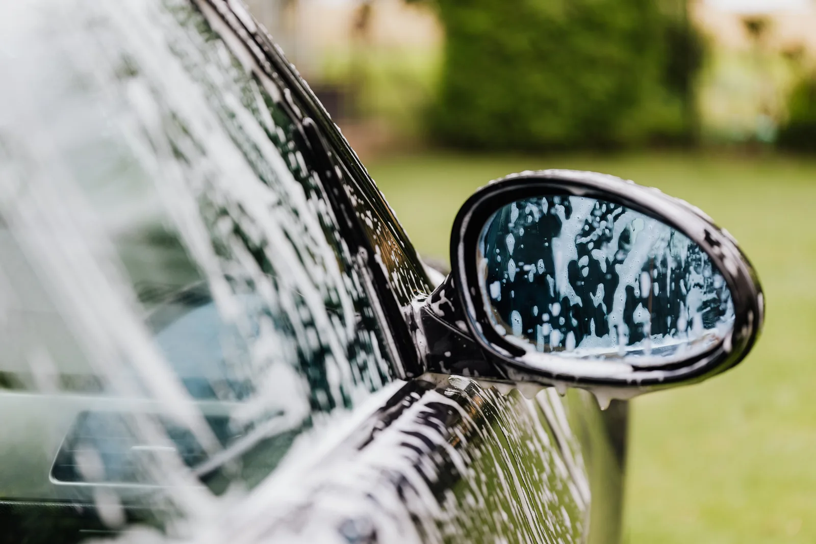 A detailed view of a car side mirror with soap suds, highlighting car wash detail. Quality control in a car wash owners: how owners check the work