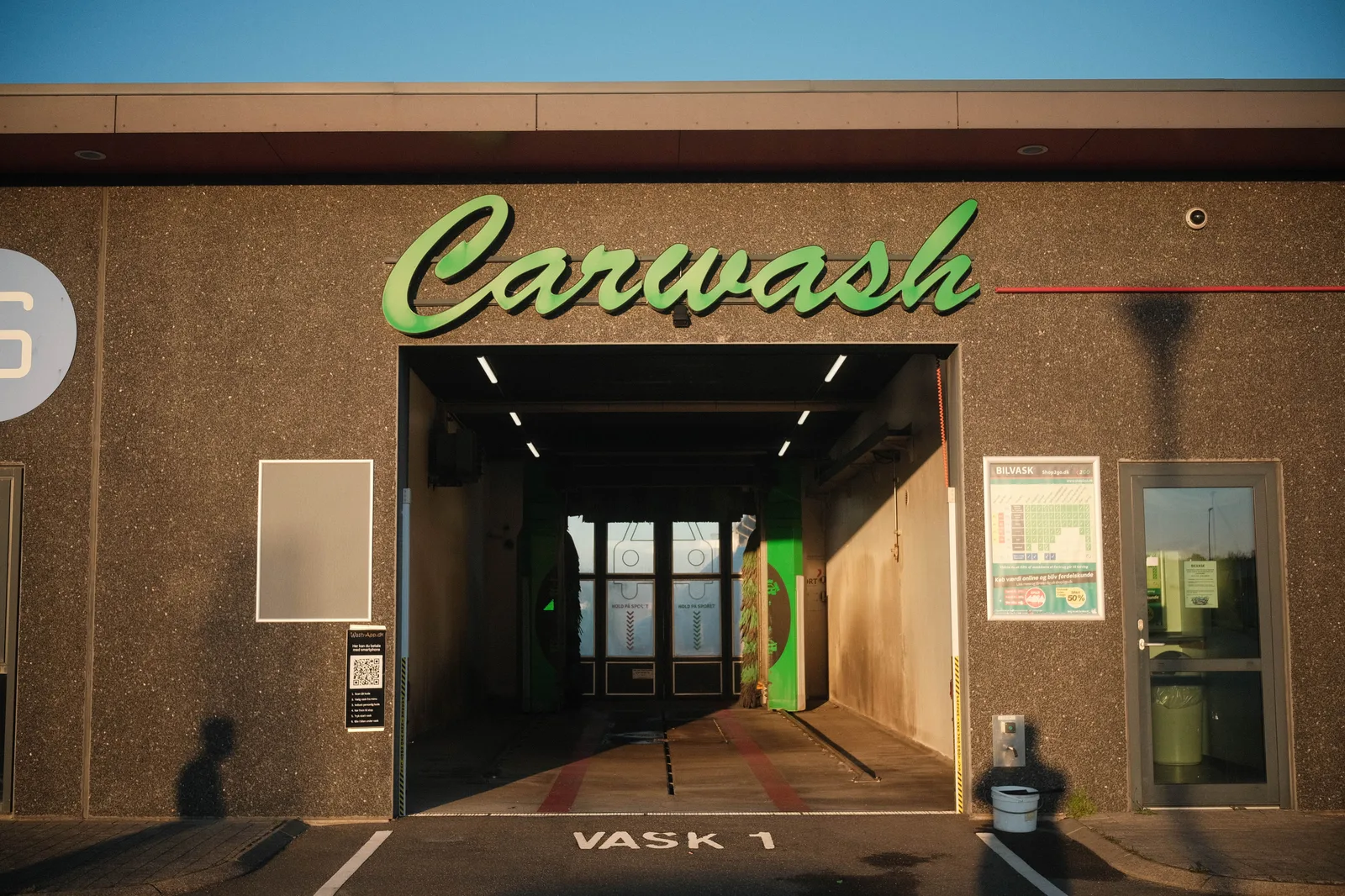Exterior view of a carwash in Norway, featuring modern design and ambient sunset lighting. Car wash business location strategy: traffic, stacking and site checks