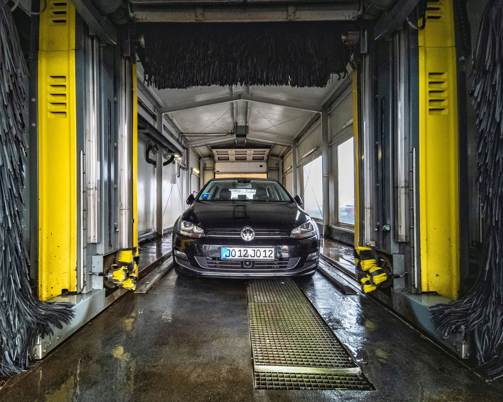 A black car undergoing a thorough cleaning in an automated car wash facility. How to keep car wash jobs on time for a small operation