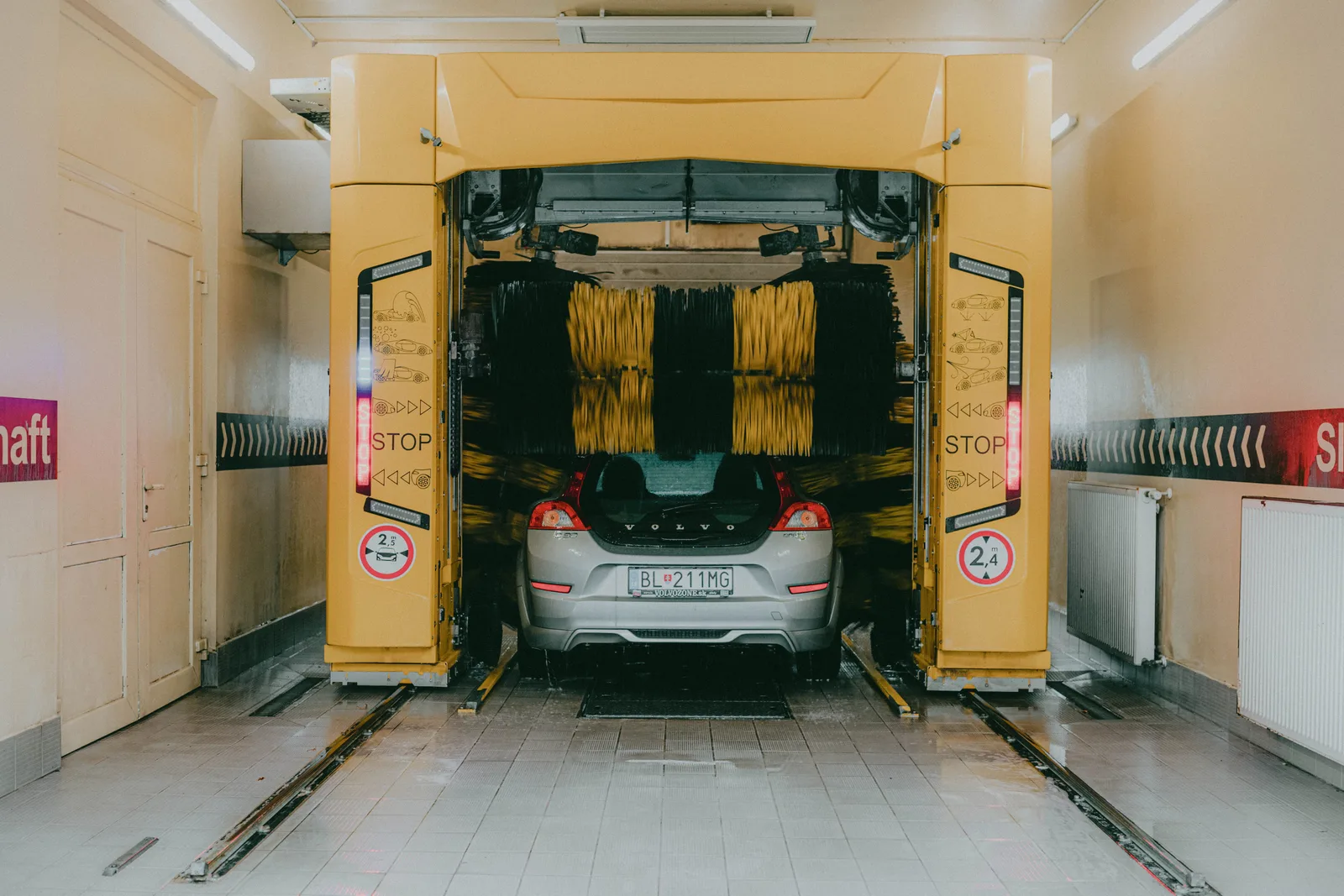 A car undergoing a cleaning process in an automated car wash station with a yellow gantry machine. How to Increase Car Wash Bay Throughput Without Adding Equipment